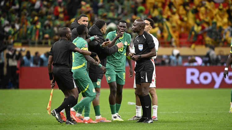 Senegal players argue with the referee